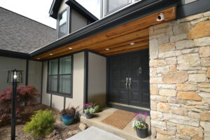 Entrance of ranch-style home with double doors flanked by stucco siding on one side and stone siding on the other