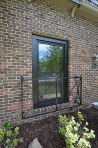 Exterior shot of double-hung window with black fiberglass frames installed in brick wall