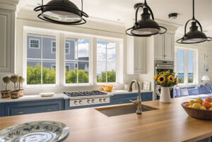 Interior view of upscale kitchen with three sets of beautiful double-hung windows over the range looking out and a set of casement windows in the dinette area