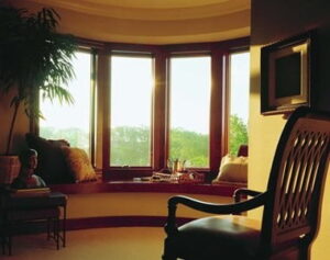 Bow window configuration shown from interior seating area on an upper story looking out on woods